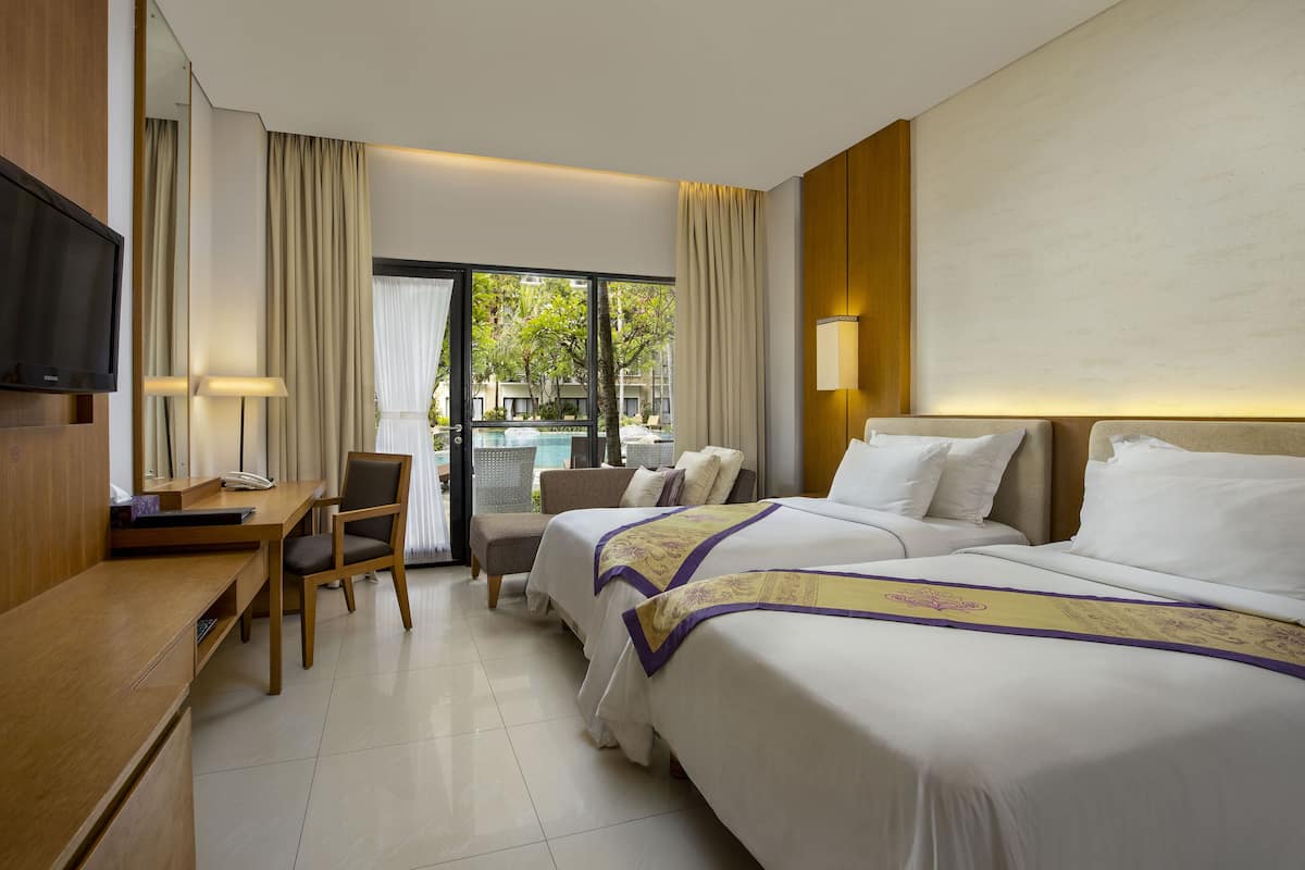 A hotel room with a bed, desk, chair, and a TV.