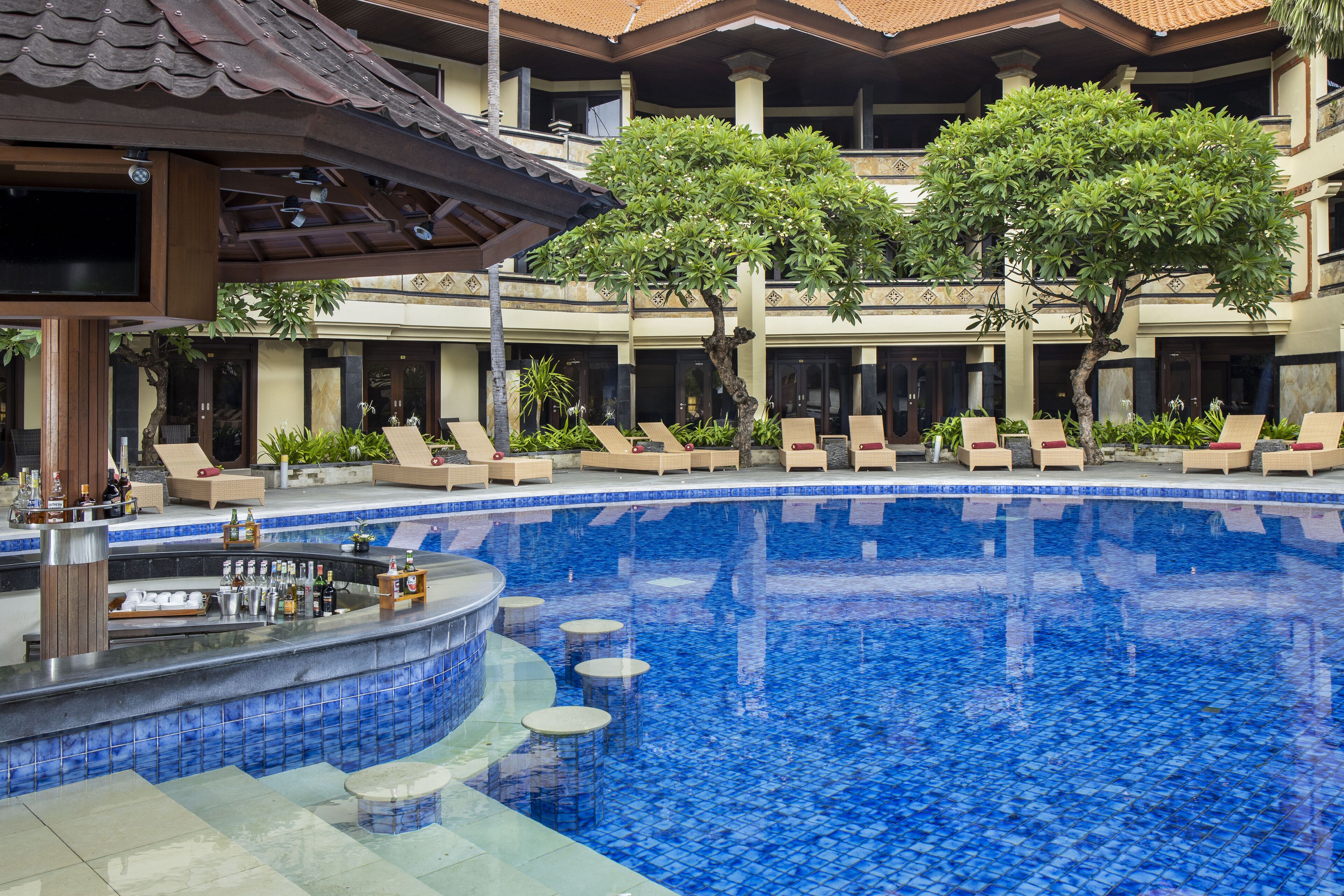 A pool area with lounge chairs, a bar, and a covered seating area.