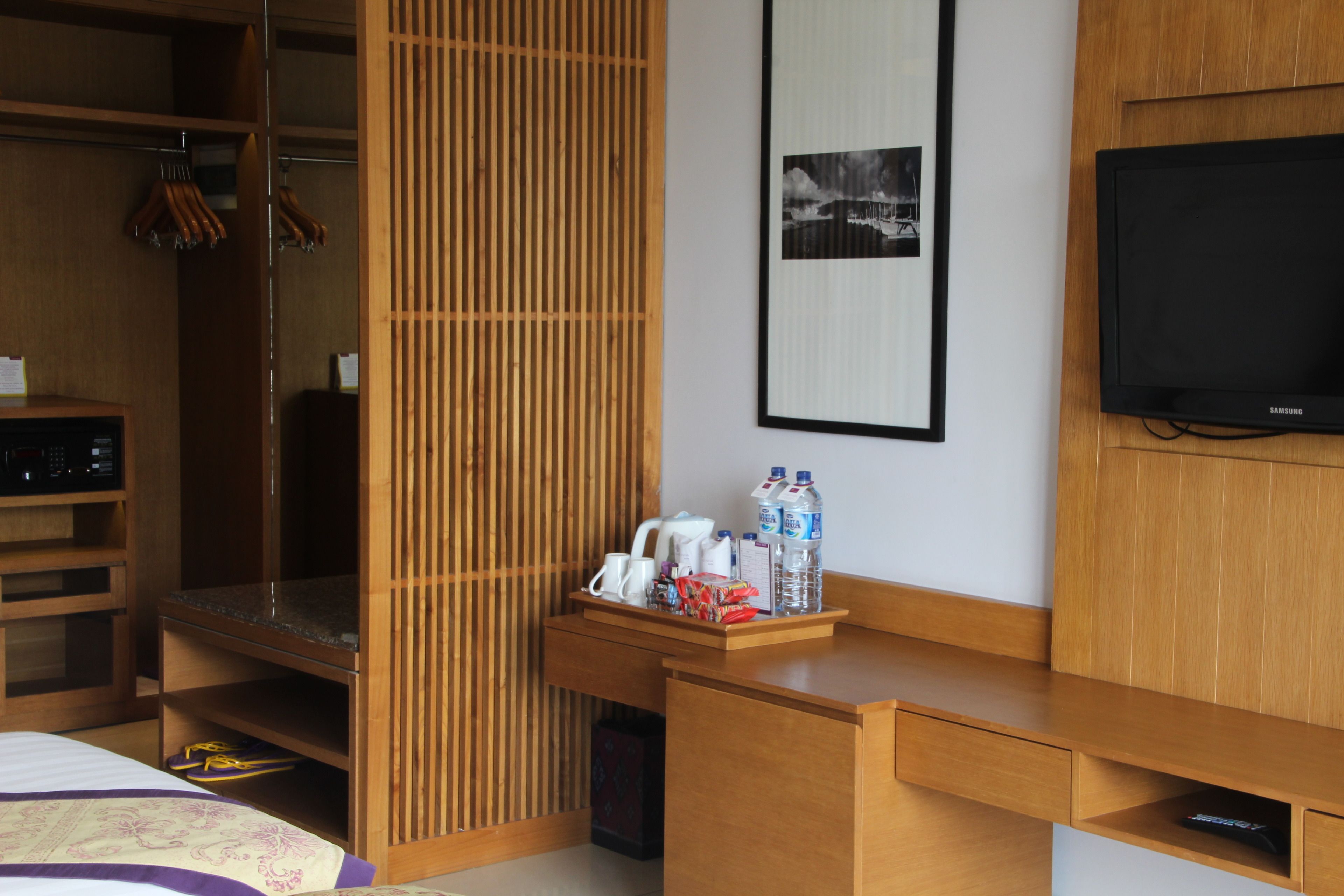 Une chambre d’hôtel avec un bureau en bois, une télévision, une armoire et un lit.