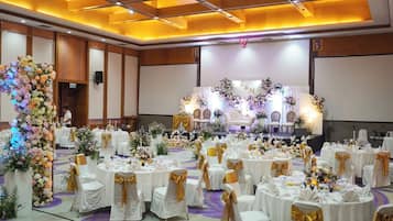 A banquet hall with round tables, white tablecloths, and gold sashes.