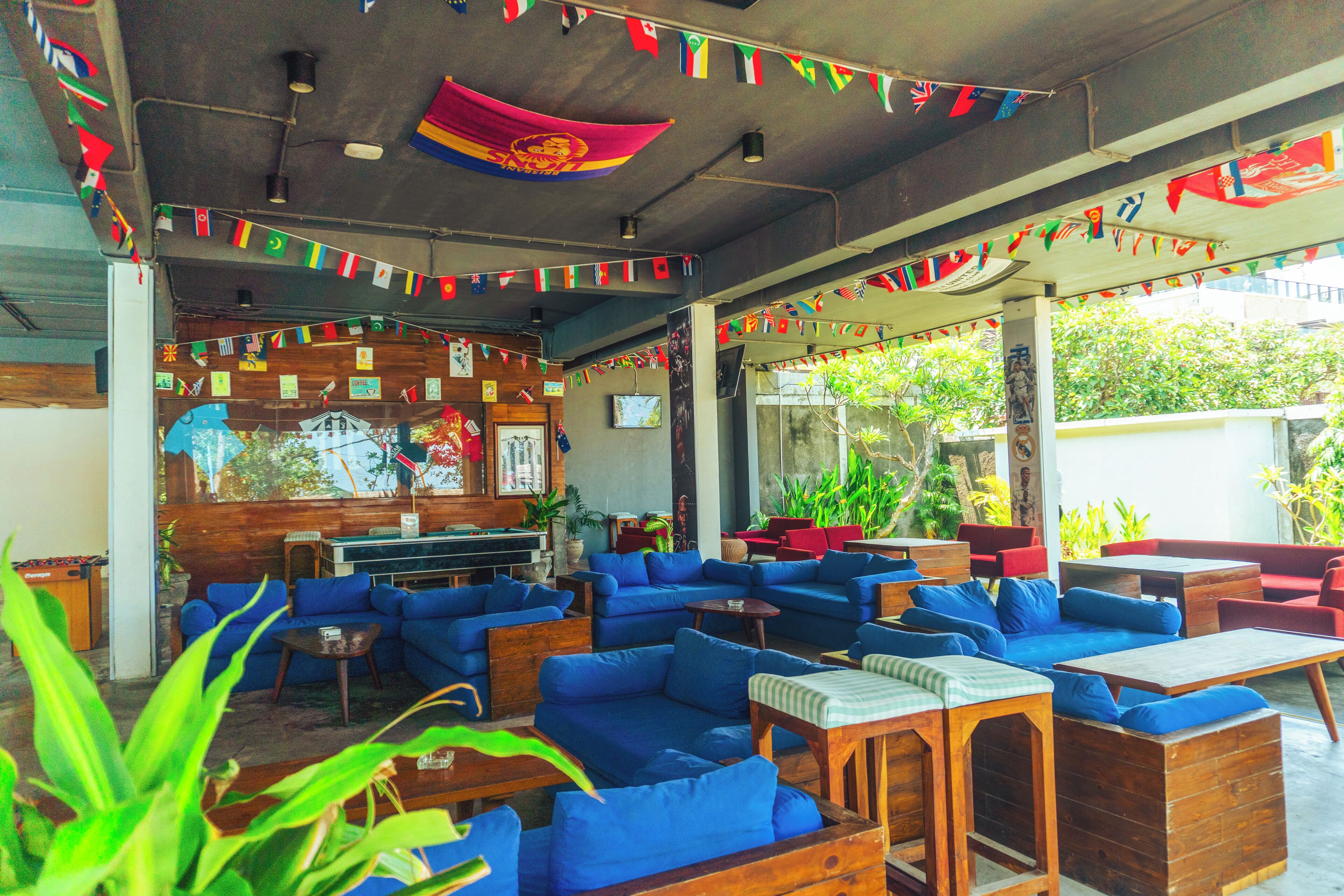 Ein Restaurant mit blauen Sofas und Holztischen, dekoriert mit Flaggen.