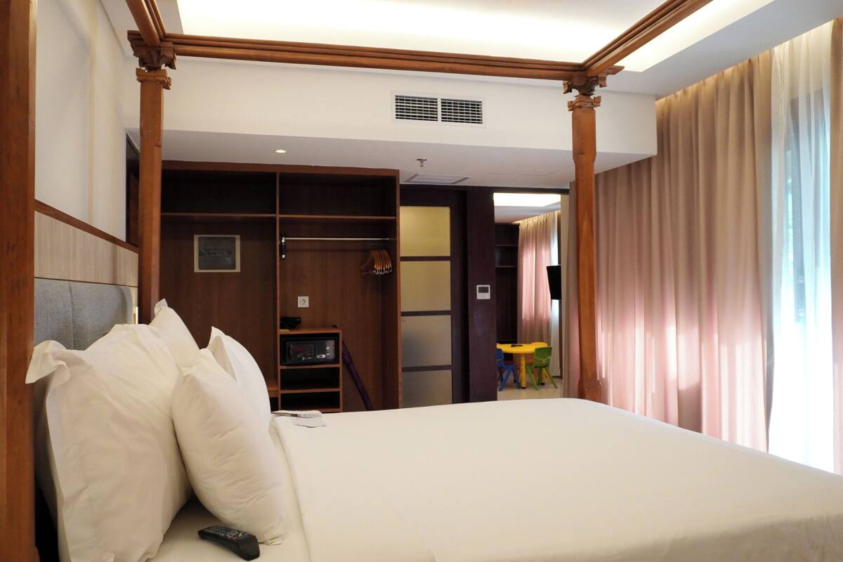 A hotel room with a large bed, a wardrobe, a desk, and a chair.