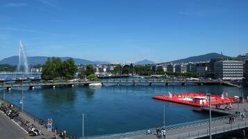 A waterfront area with a fountain, a red boat dock, and a bridge.