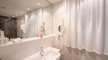 Un baño moderno con lavamanos blanco, espejo y cortina de ducha.
