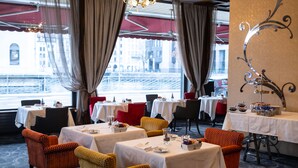 A restaurant with tables set for dining, chairs, and a decorative wall piece.