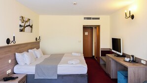 A hotel room with a bed, bedside table, TV, and a desk with a chair.