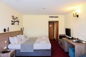 A hotel room with a bed, bedside table, TV, and a desk with a chair. - Hotel Mediterran (Budapest)