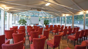 A conference room with red chairs arranged in rows, a whiteboard, and a projector screen.
