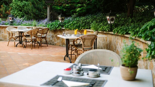 An outdoor patio with wicker furniture and a table set for dining.