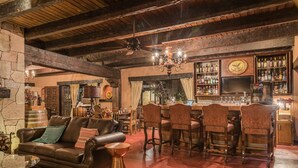 A rustic bar area with wooden beams, a leather sofa, and a bar with stools. - Hotel Mision Cerocahui by Balderrama Hotel Collection (Urique)
