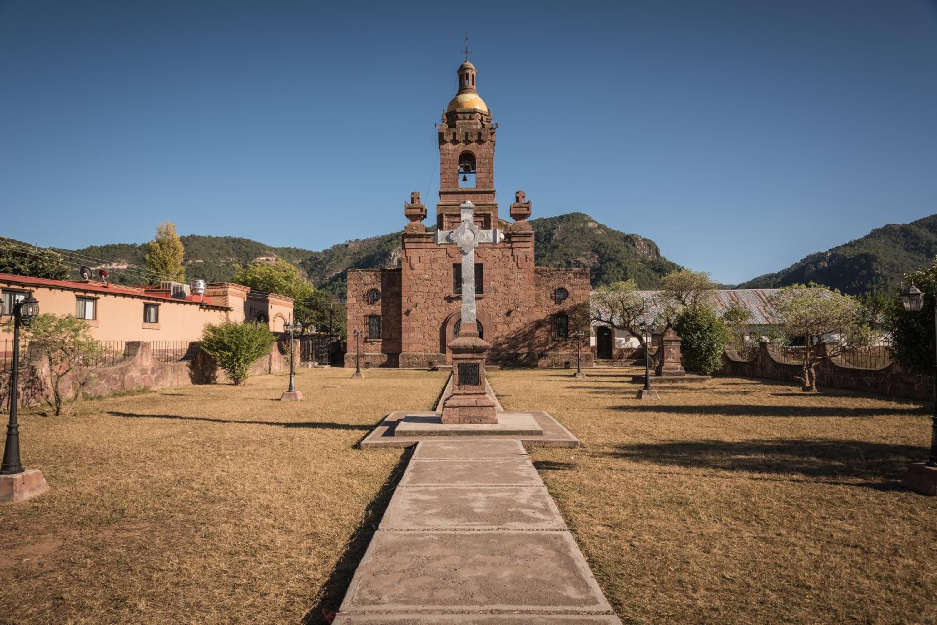 A church with a bell tower and a cross in front.