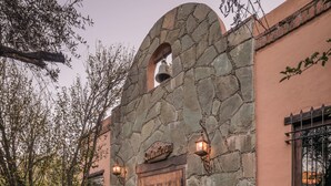 A stone facade with a wooden door, a stone archway, and a small bell. - Hotel Mision Cerocahui by Balderrama Hotel Collection (Urique)