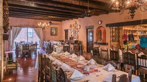 A restaurant with long tables set for dining, wooden beams on the ceiling, and a variety of dishes displayed on the walls. - Hotel Mision Cerocahui by Balderrama Hotel Collection (Urique)