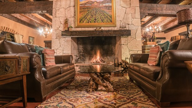 A cozy living room with a stone fireplace, leather sofas, and a rustic wooden coffee table. - Hotel Mision Cerocahui by Balderrama Hotel Collection (Urique)