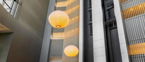 A modern interior with high ceilings, vertical wooden slats, and hanging spherical light fixtures.