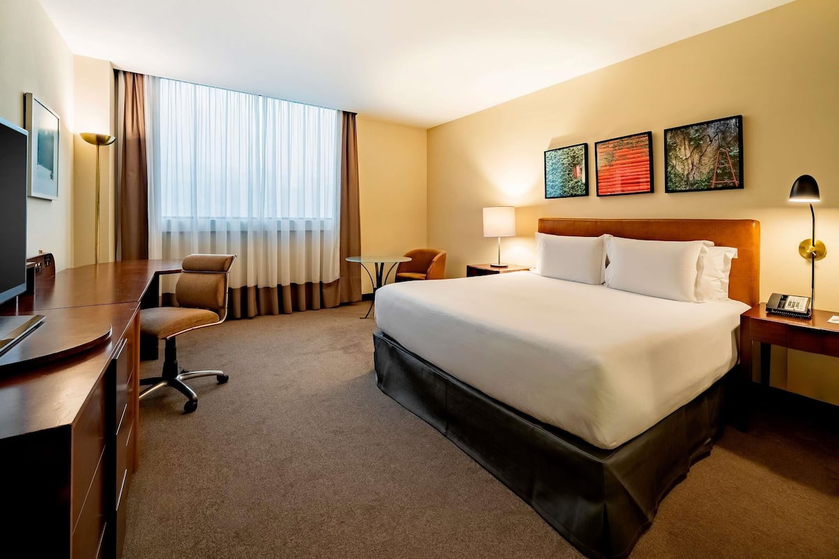 A hotel room with a bed, desk, chair, and a television.