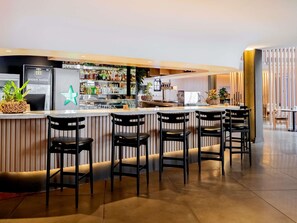 A bar area with a counter, bar stools, and a variety of bottles.