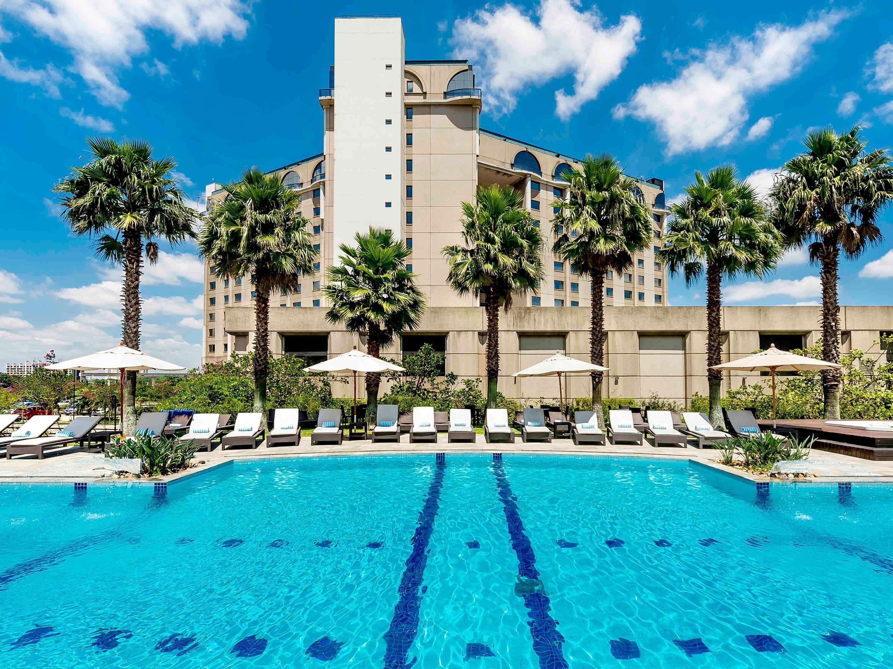 Una piscina al aire libre, sombrillas, sillones reclinables de piscina