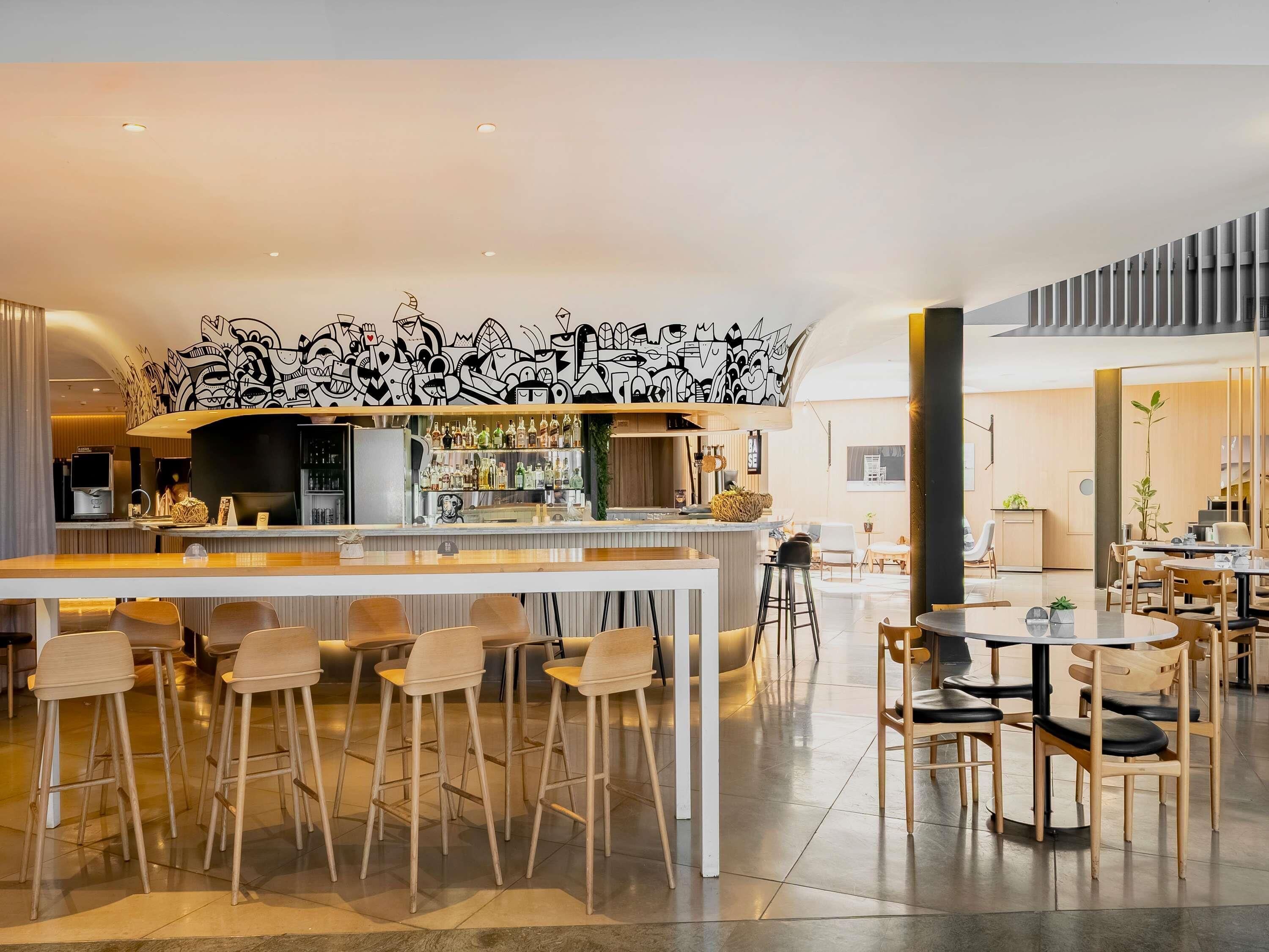 A modern bar area with a graffiti wall, bar stools, and a counter with a variety of bottles.