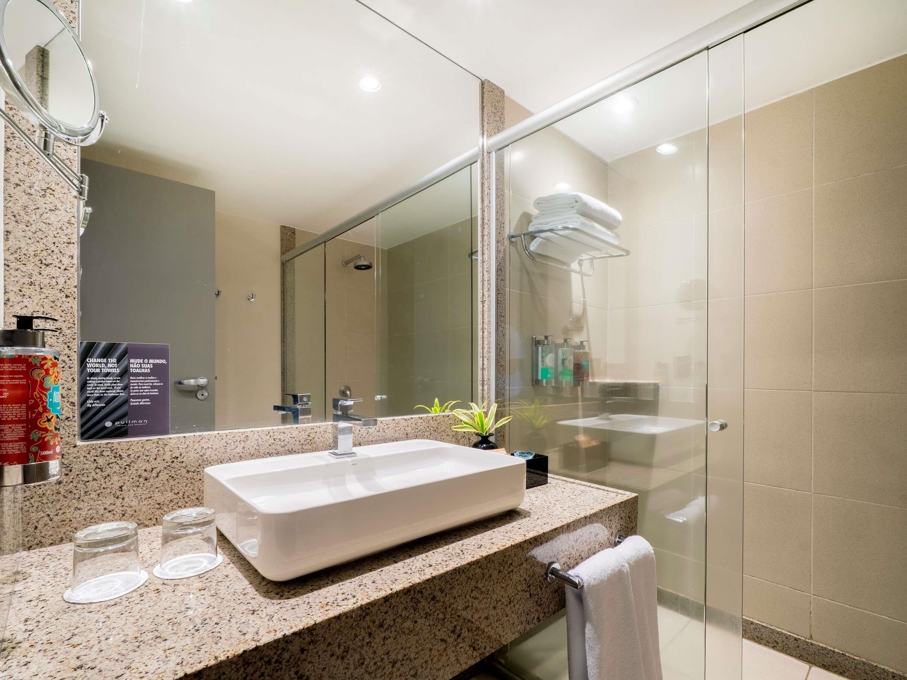 Un baño moderno con un lavamanos grande, cabina de ducha de vidrio y un espejo.
