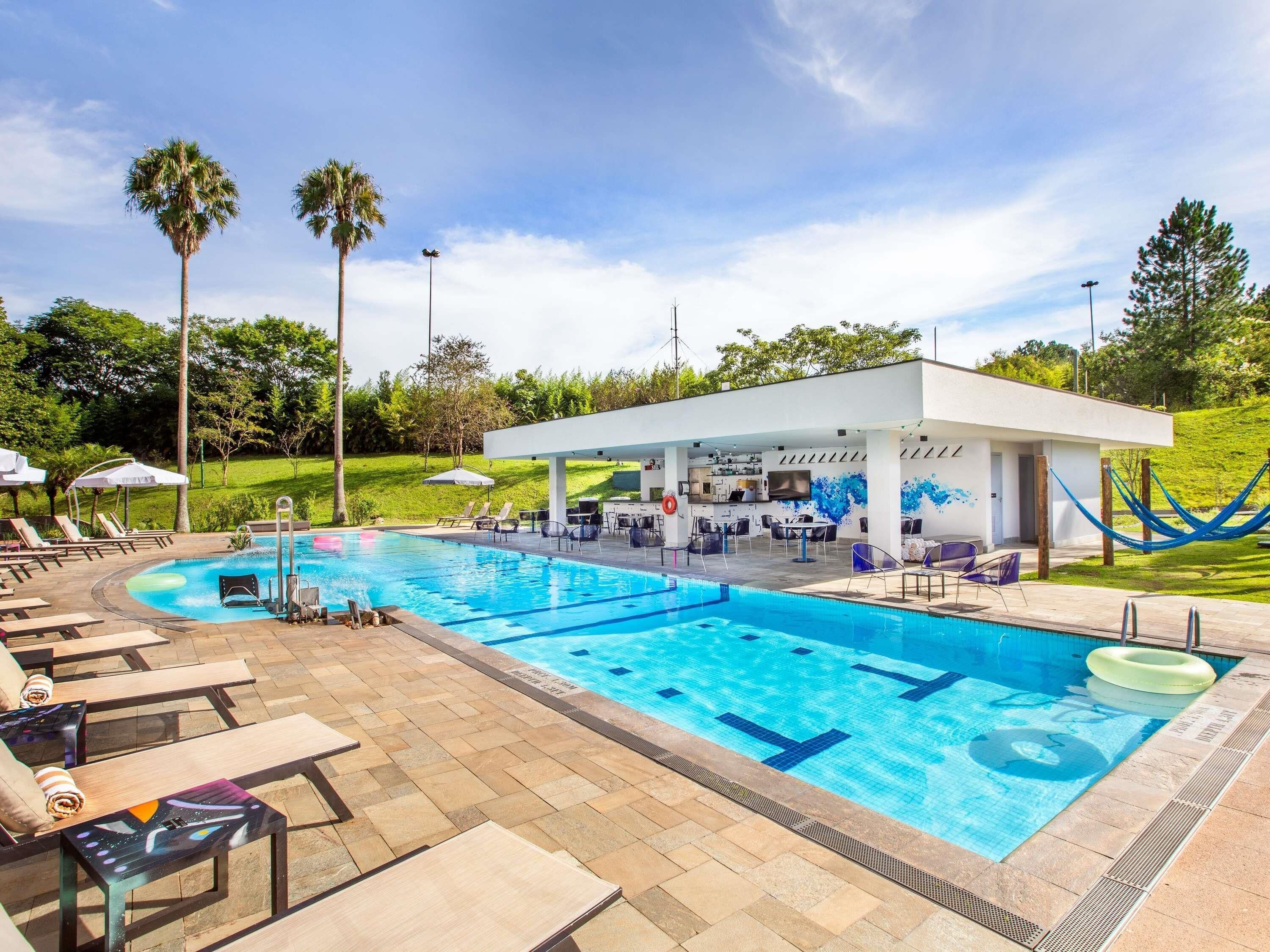 A pool area with lounge chairs, a bar, and a covered seating area.