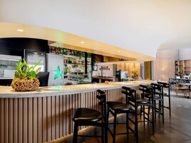 Una zona de bar con taburetes, mostrador y un refrigerador con un logotipo.