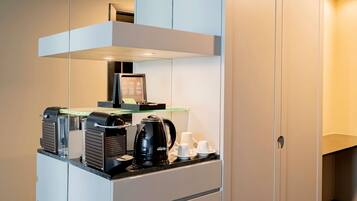 A compact kitchenette with a coffee machine, a kettle, and a small refrigerator.