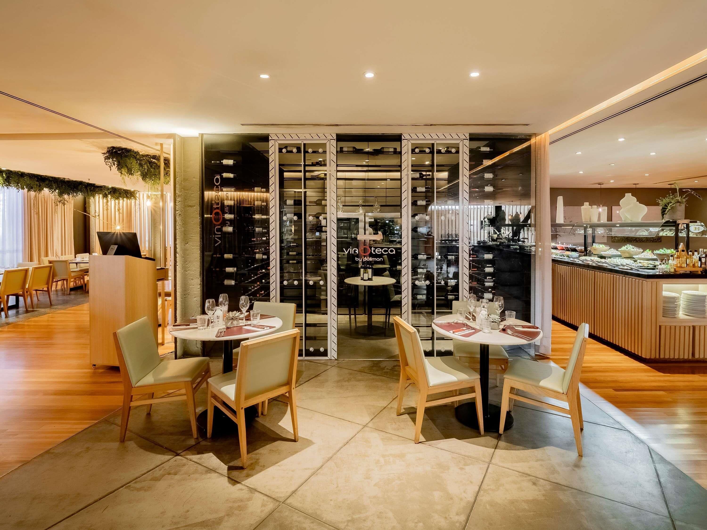 Ein Restaurant mit Holztischen und -stühlen, einer Weinauslage und einem Buffet.