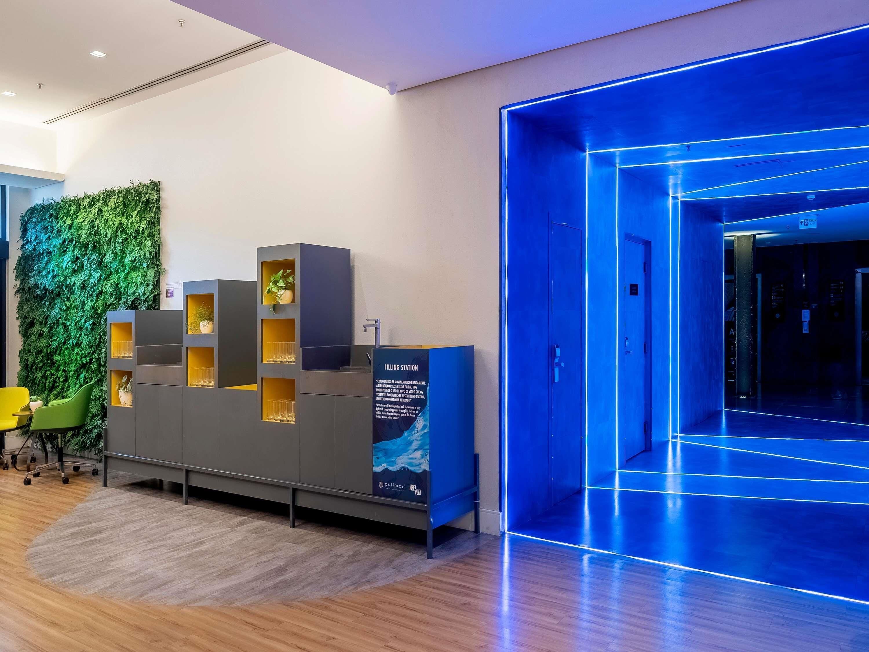 A reception area with a green wall, a blue-lit entrance, and a seating area with chairs.