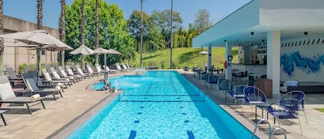 Alberca al aire libre, sombrillas en la alberca y camastros