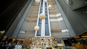 A modern hotel lobby with a central staircase, multiple seating areas, and a variety of decorative elements. - Pullman São Paulo Guarulhos Airport (Guarulhos)