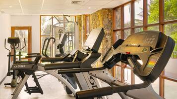 Un gimnasio con cintas de correr, una elíptica Cybex y una máquina de pesas.
