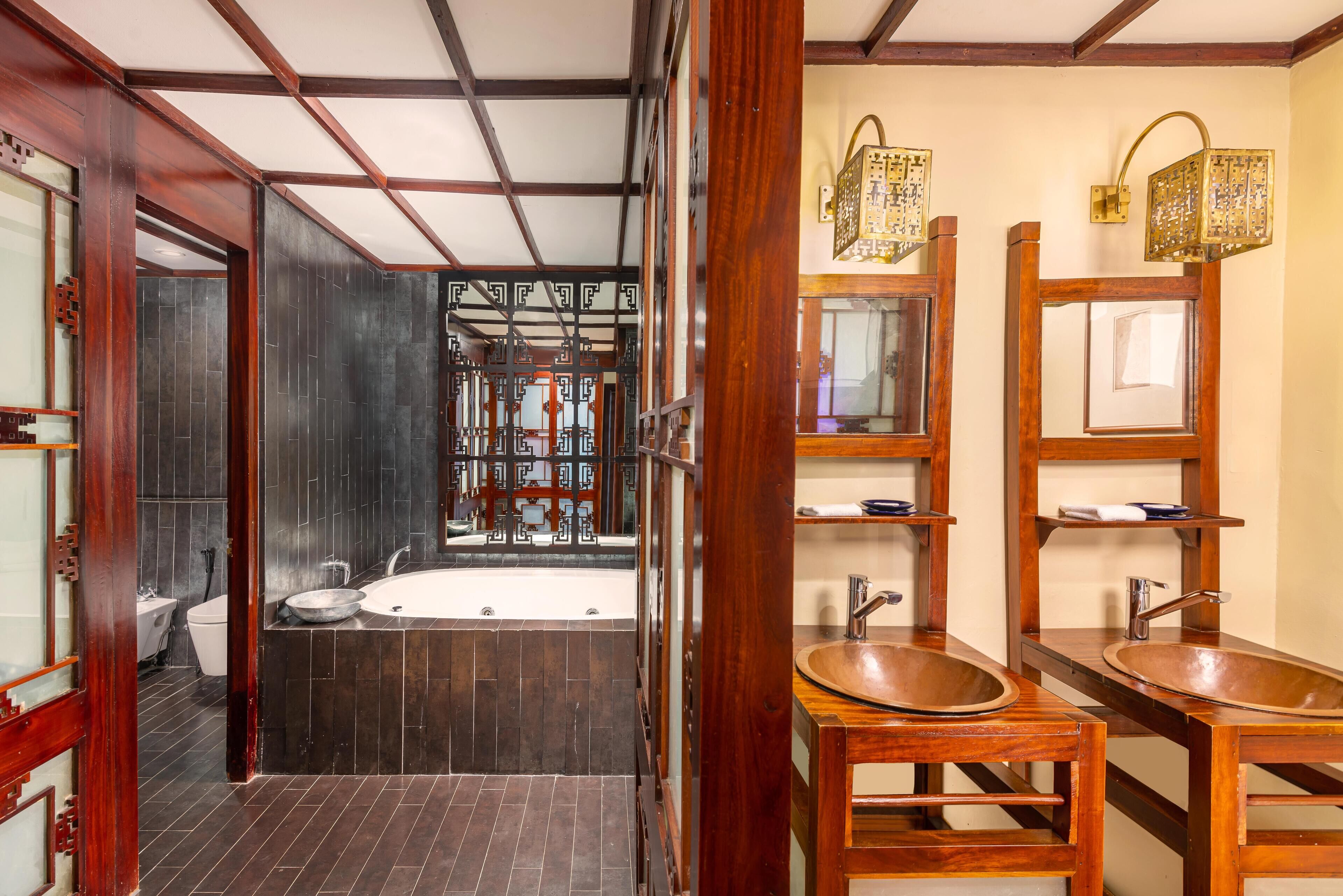 Un baño moderno con una bañera grande, tocador de madera con lavabo y apliques decorativos.