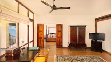 A room with a wooden table, a yellow chair, a television, and a ceiling fan.