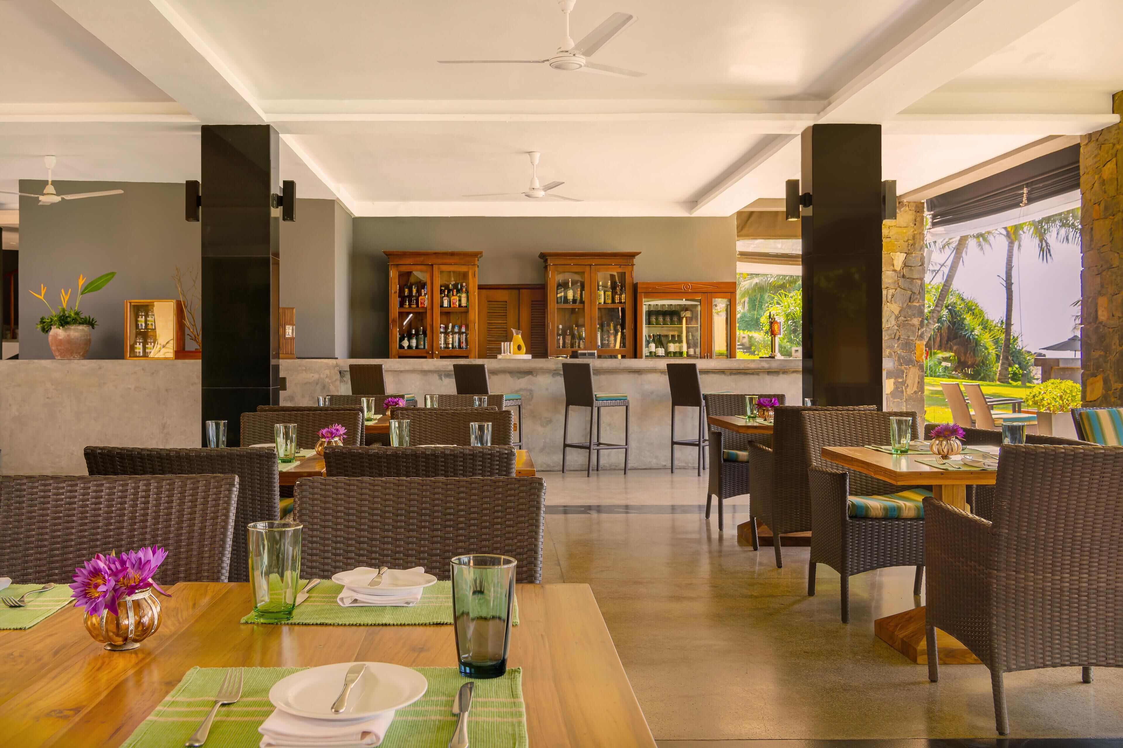 A restaurant with wicker furniture, a bar area, and a view of the outdoors.