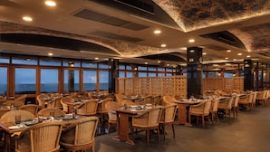 A restaurant with multiple tables and chairs, large windows, and a patterned ceiling. - Jetwing Lighthouse, A Luxury Reserve (Galle)