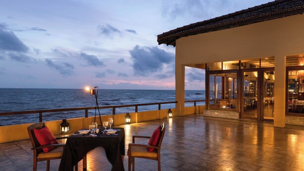 An outdoor dining area with a table set for two, overlooking the sea. - Jetwing Lighthouse, A Luxury Reserve (Galle)