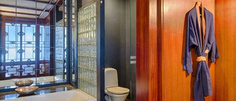 A bathroom with a bathtub, toilet, and wooden wall.