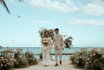 A hotel room with a thatched roof, two beds with matching blue and white bedding, wooden furniture, and a decorative wall piece. at Viceroy Riviera Maya, a Luxury Villa Resort - Adults Only