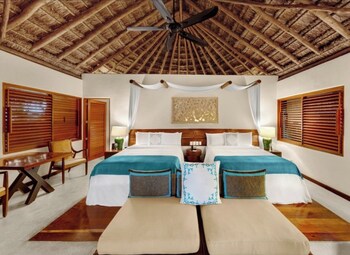 A living room with a sofa, coffee table, and TV, overlooking a pool and lush greenery. at Viceroy Riviera Maya, a Luxury Villa Resort - Adults Only