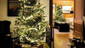 A well-lit living room with a large Christmas tree, a sofa, and a coffee table.