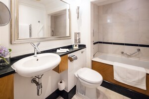 Un baño con lavamanos blanco, espejo, inodoro y bañera.