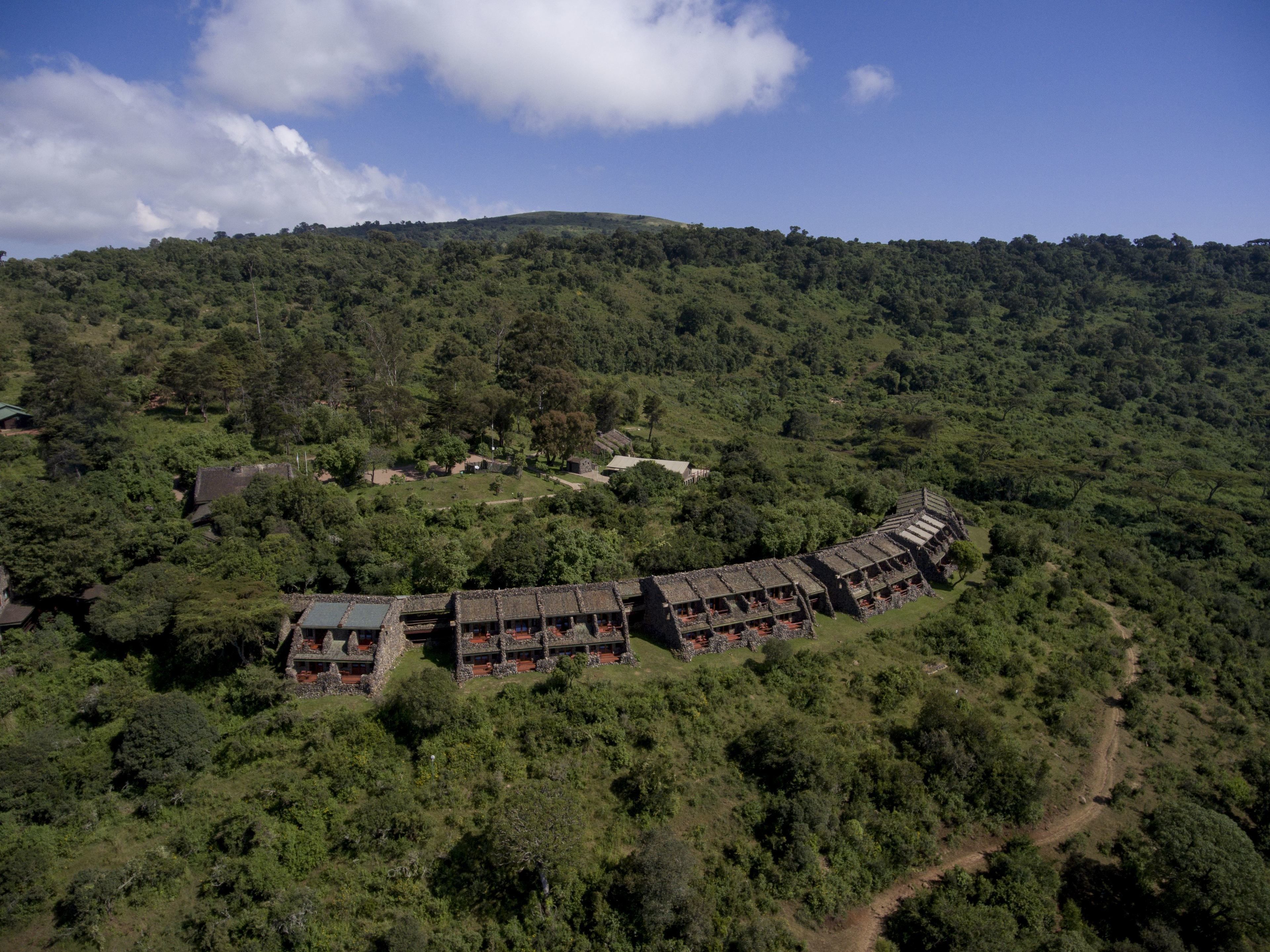 Luchtbeeld van een resort met een golvend gebouw, omringd door dicht bos.