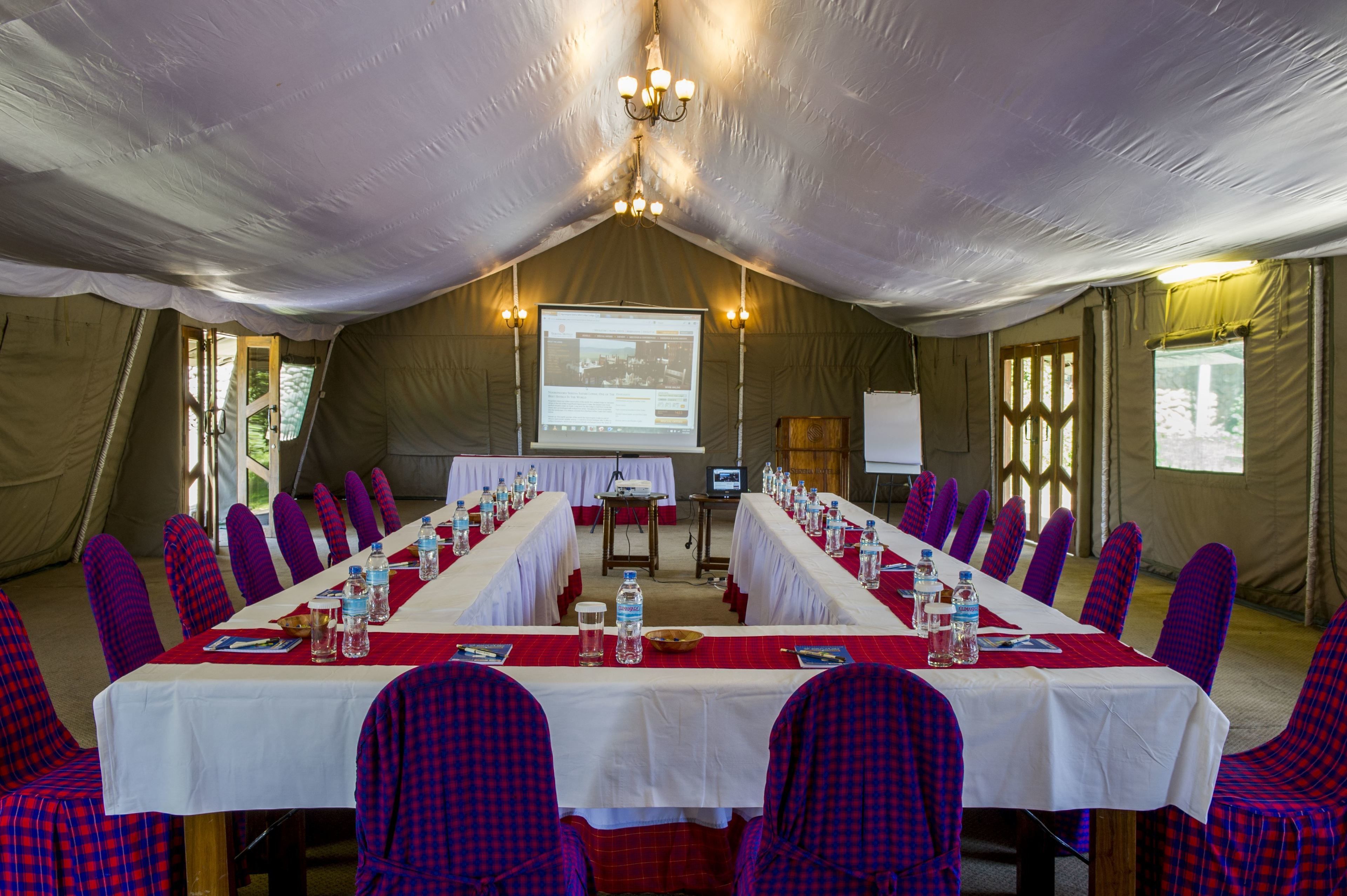 A conference room with a long table, chairs, and a projector screen.