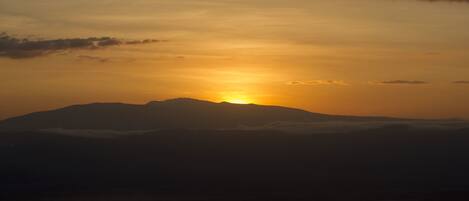 A mountain silhouette at sunset with a lake in the foreground.