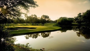 A serene golf course with a pond, surrounded by trees and well-manicured grass. - Microtel by Wyndham Tarlac (Tarlac)
