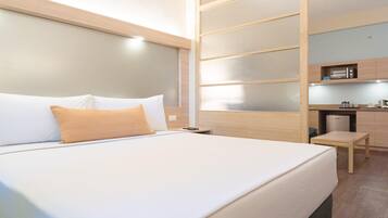 Une chambre d’hôtel équipée d’un lit, d’un bureau et d’un coin cuisine.
