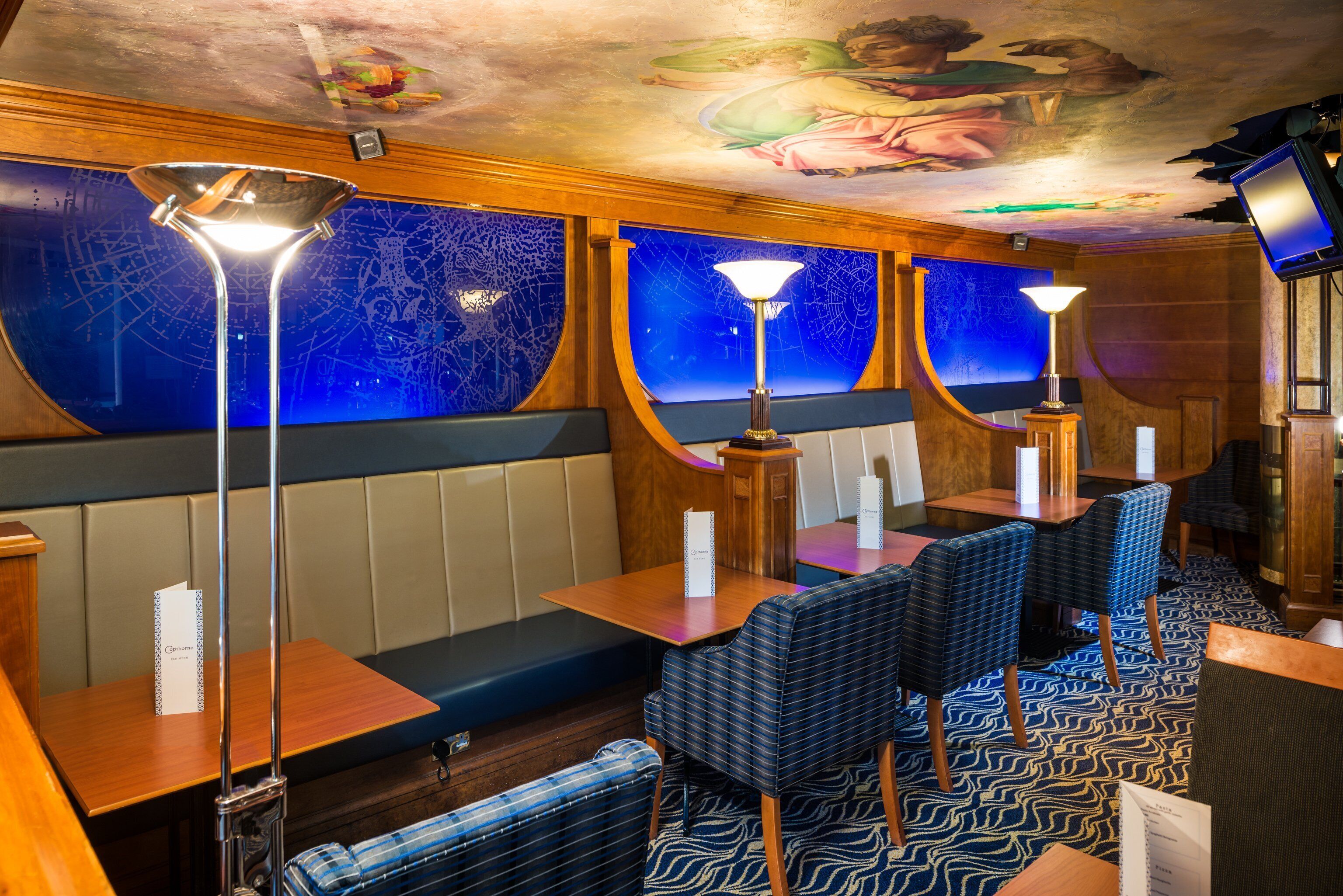 Un restaurant avec des banquettes et des tables, des chaises à motifs bleus et un plafond décoratif.