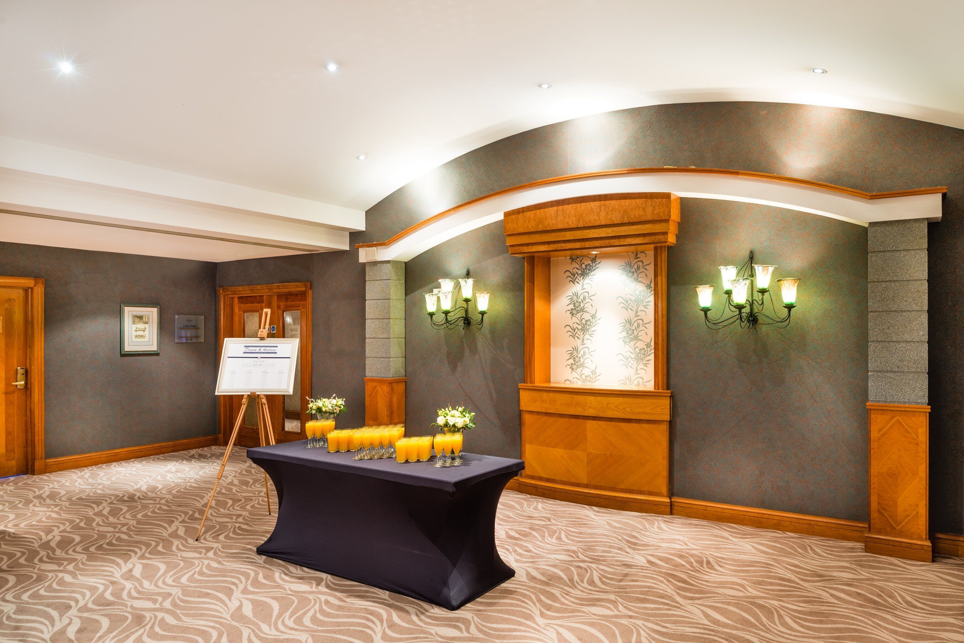 A conference room with a table set for a meeting, a whiteboard, and wall-mounted lights.