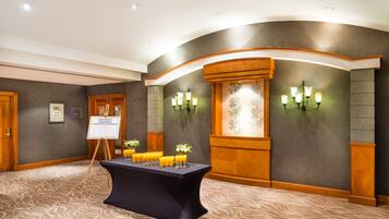 A conference room with a table set for a meeting, a whiteboard, and wall-mounted lights.